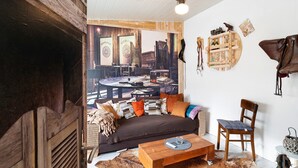 Hyggelig opholdsstue med sofa, sofabord i træ, en lænestol og en loftventilator.
