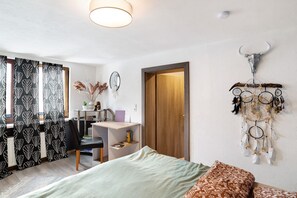 A room with a bed, desk, chair, and a wall-mounted dreamcatcher. - Apartment "Wildwest Lounge" with Pool, Terrace & Wi-Fi (Eppingen)