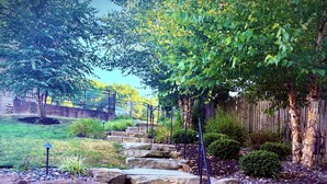 A stone staircase leading up to a house, surrounded by a wooden fence and greenery. - HEAVENLY Portage Lakes water front 4-bedroom cottage with HOTTUB, dog friendly! (Akron)