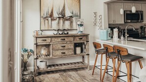 A modern kitchen with wooden flooring, a central island with bar stools, a skylight, and a sailboat painting on the wall. - HEAVENLY Portage Lakes water front 4-bedroom cottage with HOTTUB, dog friendly! (Akron)