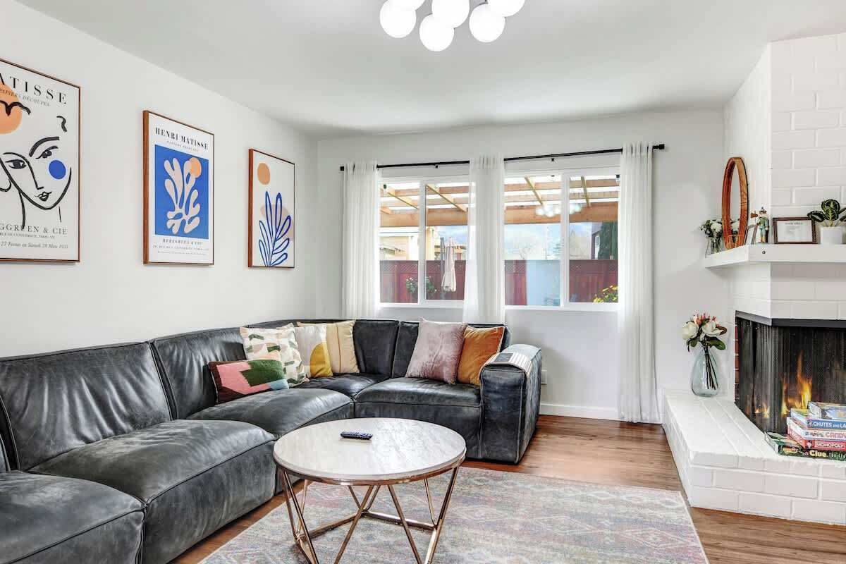 A living room with a black leather sofa, a round coffee table, and a fireplace.
