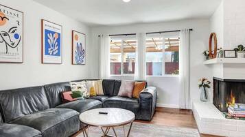 A living room with a black leather sofa, a round coffee table, and a fireplace.