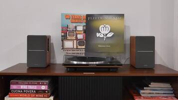 A music player with a vinyl record, two speakers, and a bookshelf with books.