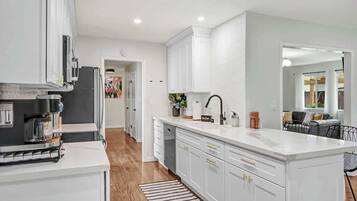 A modern kitchen with white cabinetry, a central island, and a built-in oven.