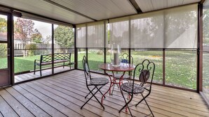 A covered patio with a table and chairs, a bench, and a view of a grassy yard. - Beautiful 4 bedroom 2 full bathroom close to everything! (Champaign)