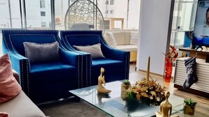 A modern living room with a blue sofa, a glass coffee table, and a television. - Ideal location Ocean View Miraflores Condo (Miraflores)