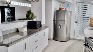 A modern kitchen with white cabinets, a stainless steel refrigerator, a microwave, and a stove. - Ideal location Ocean View Miraflores Condo (Miraflores)
