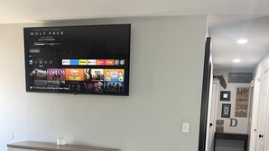 Un salon avec un téléviseur à écran plat fixé au mur, qui affiche l’interface d’un service de diffusion en continu.