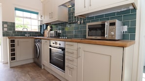 Ett modernt kök med vita skåp, en inbyggd ugn, en mikrovågsugn och en diskmaskin.