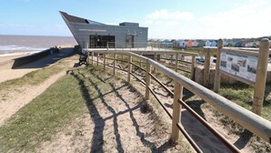 A coastal observatory with a modern design, a viewing platform, and a sandy path leading to the beach. - 57 Cherry Park (Skegness)