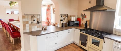 A modern kitchen with white cabinetry, a stainless steel range hood, a built-in oven, and a microwave.