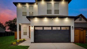 Een modern herenhuis met garage, een verzorgd gazon en een heldere lucht.
