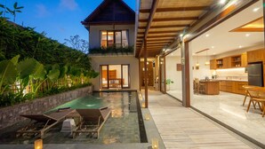 Una casa moderna con piscina, terraza de madera y espacio para la cocina.
