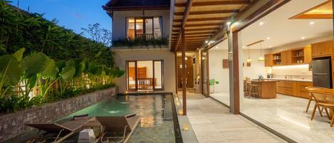 Una casa moderna con piscina, terraza de madera y espacio para la cocina.