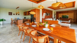 Un comedor amplio con una larga mesa de madera, sillas de mimbre y lámparas colgantes de mimbre.