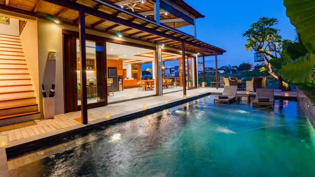 Un moderno resort con piscina, mobiliario exterior y zona de patio techada.