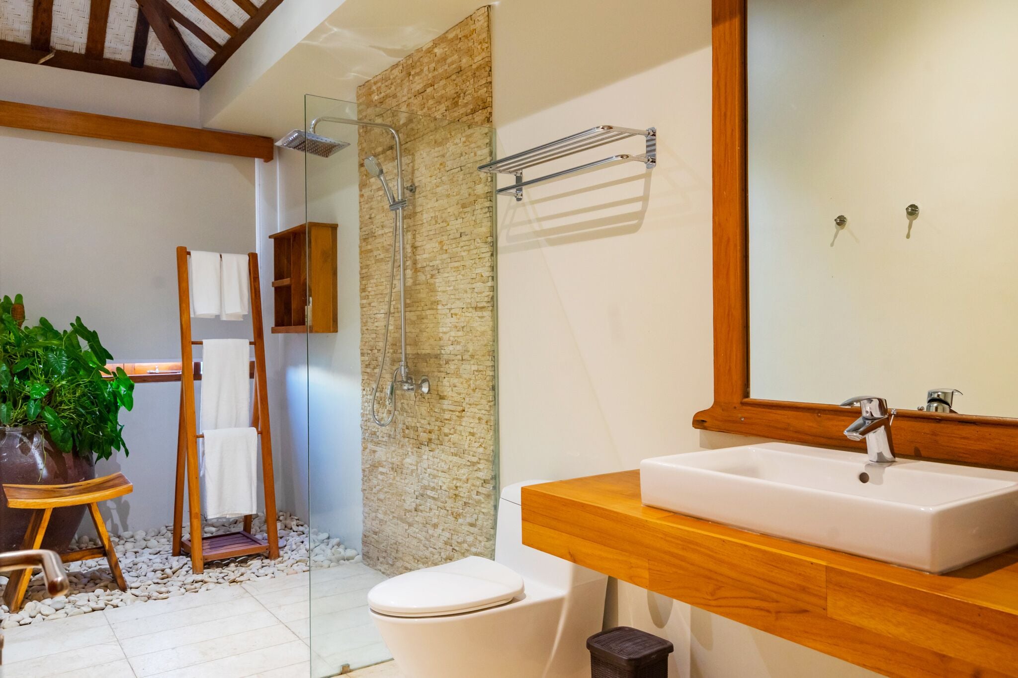 A modern bathroom with a wooden vanity, a glass shower enclosure, and a large mirror.