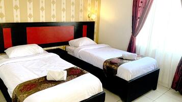 A hotel room with two beds, each with white linens and a red headboard.
