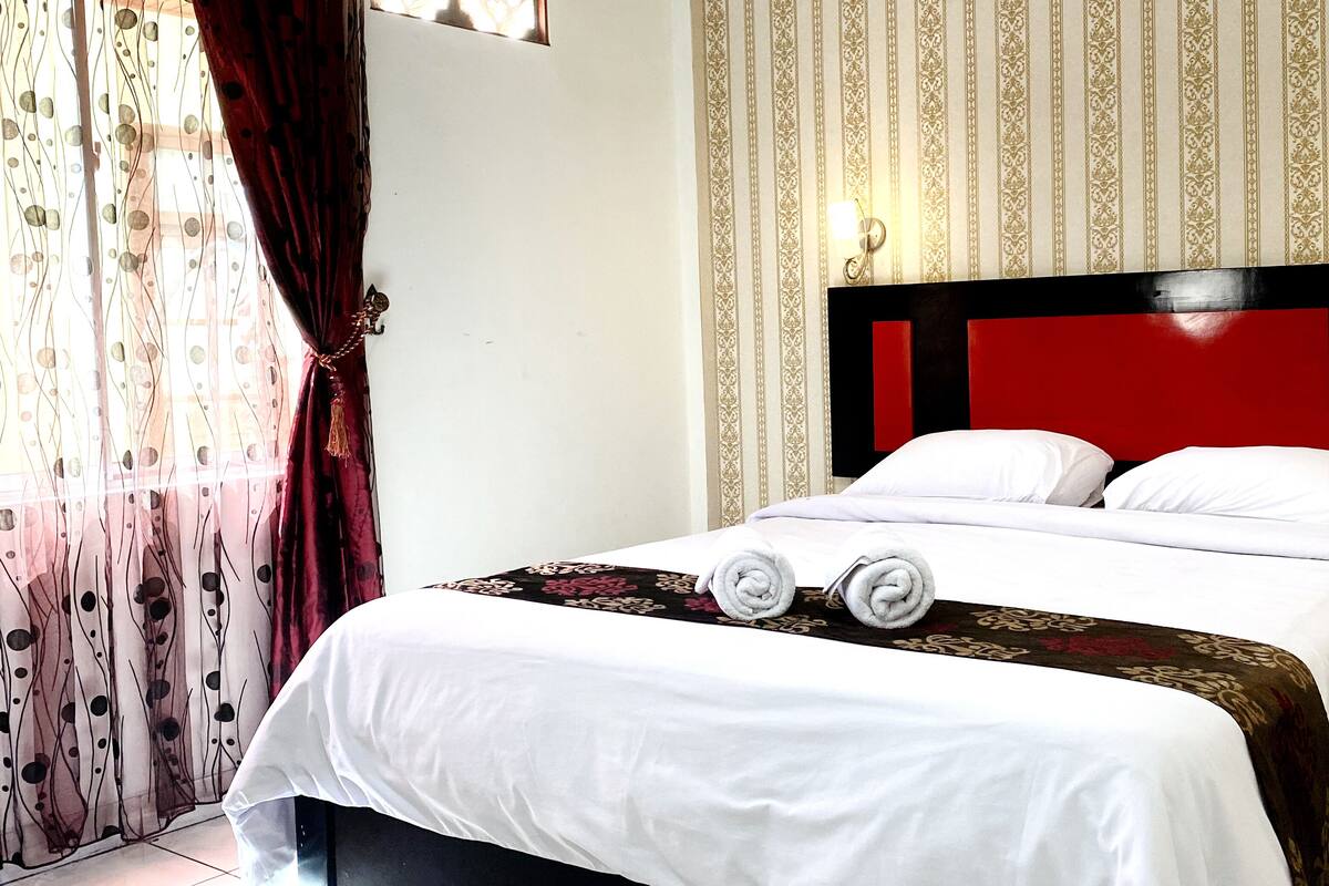 A hotel room with a bed, a nightstand, and a telephone.