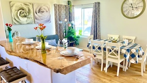 Un comedor con una isla de madera, sillas blancas y mantel a cuadros.