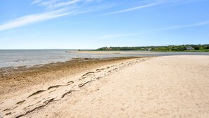 A beach with footprints leading to the water, a clear sky, and a distant building. -  Southampton Gem House with Beautiful Heated Pool (Southampton)
