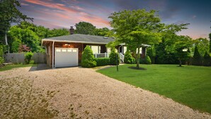 A house with a garage, a well-maintained lawn, and a gravel driveway. -  Southampton Gem House with Beautiful Heated Pool (Southampton)