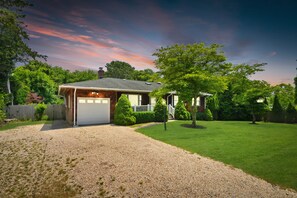 A house with a garage, a well-maintained lawn, and a gravel driveway.