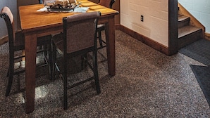Un coin repas avec une table et des chaises en bois, un lustre et un escalier avec une fenêtre.