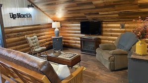 L’intérieur d’une cabane en rondins, avec une cheminée, un téléviseur et une pancarte sur laquelle on peut lire « UpNorth ».