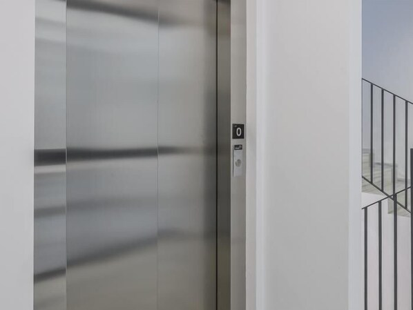 A modern elevator with a metallic finish and a control panel with a button marked '0'.