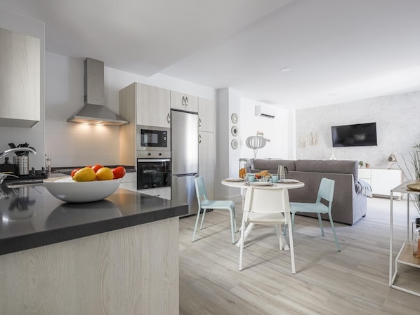 A modern kitchen with a central island, built-in appliances, and a dining area with a round table and chairs.