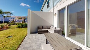 Un patio moderno al aire libre con terraza de madera, zona de estar integrada y un amplio ventanal corredero.