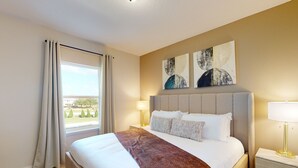 Habitación de hotel con una cama grande, una mesita de noche, una lámpara y una obra de arte en la pared.