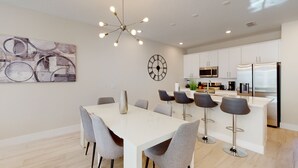 Una cocina moderna con armarios blancos, un refrigerador de acero inoxidable y un microondas.