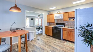 A modern kitchen with wooden cabinets, a stainless steel refrigerator, and a dining area with a table and chairs.