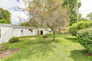 A row of mobile homes with a grassy yard and a tree in the center.