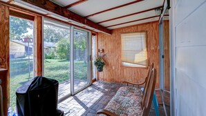 A covered porch with a wooden bench, a grill, and a potted plant.
