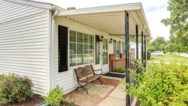 A house with a covered porch, a bench, and a small garden area.