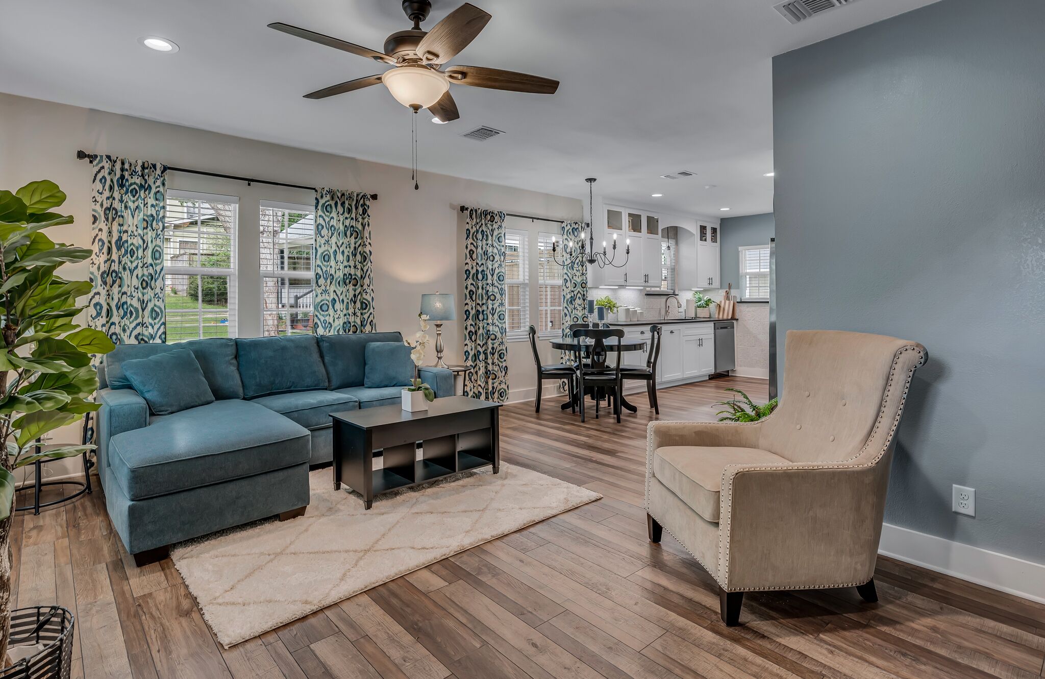 A living room with a sofa, armchair, coffee table, and a dining area with a table and chairs.