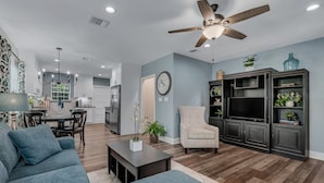 Una sala de estar moderna con sofá, sillón, mesa de centro y mueble para televisión.