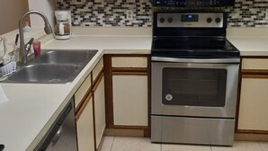 Uma cozinha equipada com micro-ondas, fogão, pia e cafeteira.