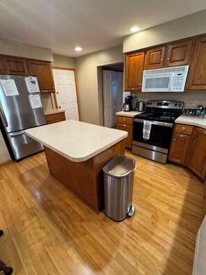 A kitchen with wooden cabinets, stainless steel appliances, a central island, and a trash can. - 5-BR House/Backyard/2 Lakes/4 Beaches/3Pools/Playgrounds (Pocono Lake)