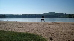 A beach with a lifeguard chair and a dock. - 5-BR House/Backyard/2 Lakes/4 Beaches/3Pools/Playgrounds (Pocono Lake)