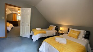 A hotel room with two beds, each with a yellow bedspread and white pillows, including one with the word "Smile". There is a nightstand with a lamp between the beds, and a door leading to another room. - 5-BR House/Backyard/2 Lakes/4 Beaches/3Pools/Playgrounds (Pocono Lake)