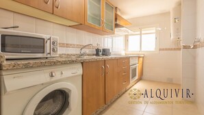 A kitchen with a microwave, washing machine, and a coffee maker on the counter. - Penthouse with Terrace San Julian Cordoba ⭐⭐⭐⭐ (CORDOBA)