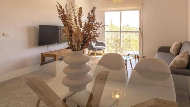 A modern living room with a glass dining table, a sofa, a TV, and a large window with a view. - Penthouse with Terrace San Julian Cordoba ⭐⭐⭐⭐ (CORDOBA)