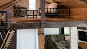 A loft-style room with a sloped ceiling, a wooden ceiling beam, a sofa, a small table, and a fireplace.