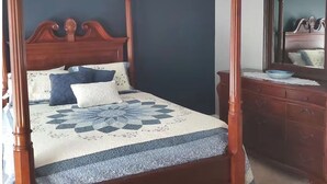 Una cama con dosel, un ventilador de techo, un aparador y un espejo en un dormitorio.