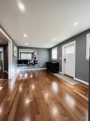 Una habitación amplia con suelo de madera, una zona de cocina y una sala de estar con sillas.