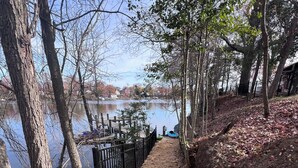 A pathway leading to a lake with a wooden fence, trees, and a boat. - CHeerful 3-bedroom waterfront home (Riviera Beach)